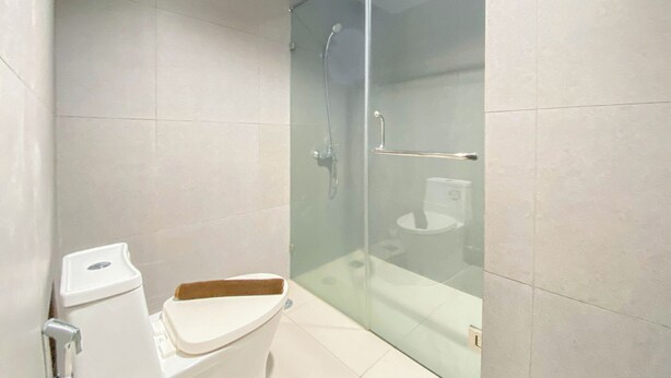 Een moderne badkamer met een douchecabine van glas, toilet en wastafel.