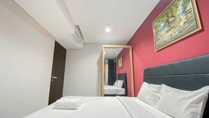 A hotel room with a bed, a mirror, a painting, and a door. - Elegant and Comfortable 1BR at Patraland Amarta Apartment (Ngaglik)