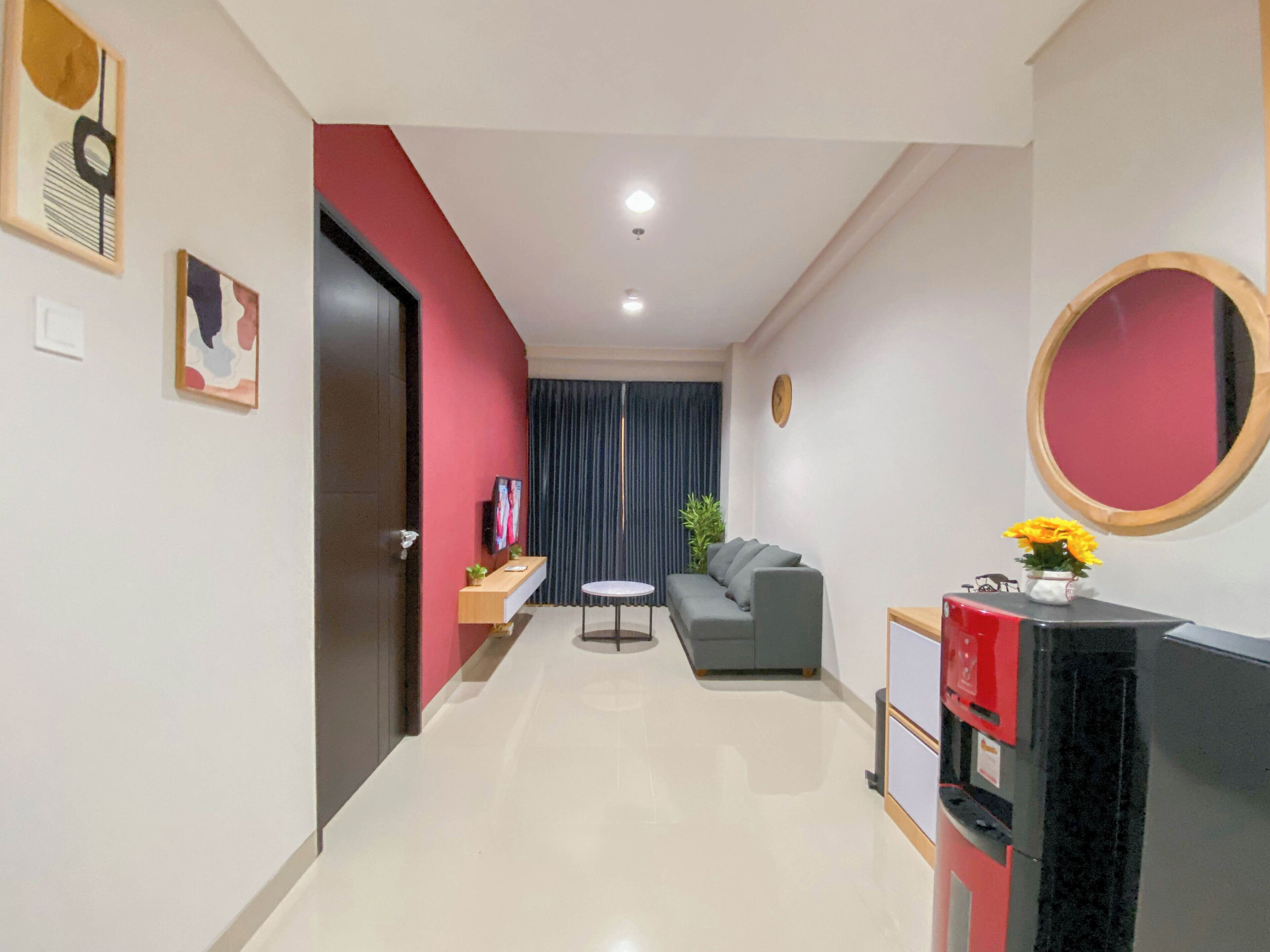 A modern living room with a grey sofa, a small round table, and a TV stand with a red cabinet.