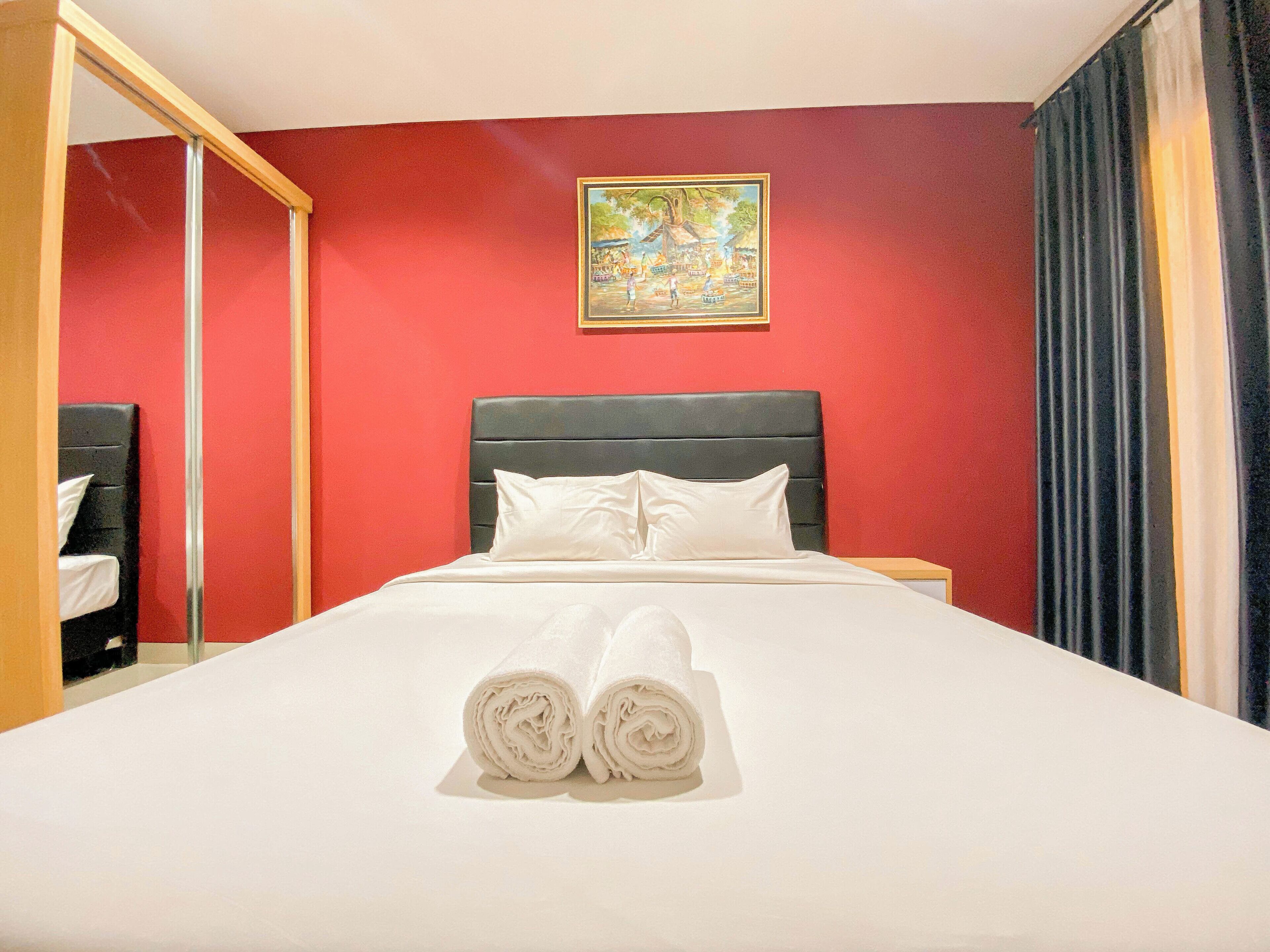 Una habitación de hotel con una cama, un cuadro en la pared y una ventana con cortinas.