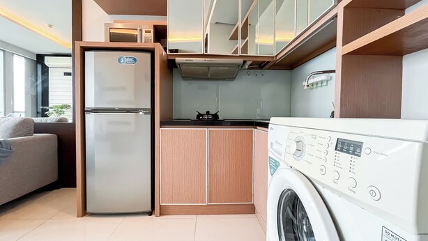 Une cuisine compacte équipée d’un réfrigérateur, d’un four à micro-ondes, d’une cuisinière et d’un lave-linge.