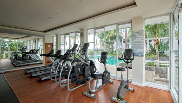 A gym with treadmills, elliptical machines, and a stationary bike. - Luxurious 1BR at Vida View Makassar Apartment (Makassar)