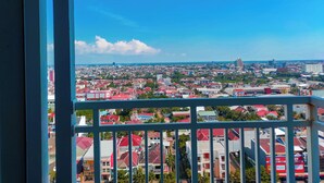 A cityscape viewed from a balcony with a railing. - Luxurious 1BR at Vida View Makassar Apartment (Makassar)