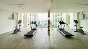 Ein Fitnessstudio mit Laufbändern und Ergometer, großen Fenstern und Blick auf Gebäude.