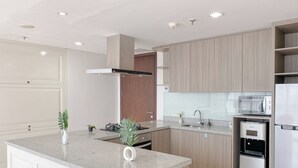 A modern kitchen with a central island, built-in appliances, and light wood cabinetry. - Nice and Comfy 2BR Apartment at Ciputra World 2 (Jakarta)