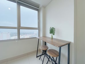 Enjoy a city view from the large window in this stylish room with a wooden table and potted plant.