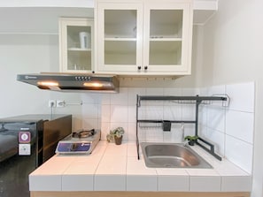Enjoy cooking in this well-equipped kitchen with a stainless steel range hood, sink, and compact countertop.