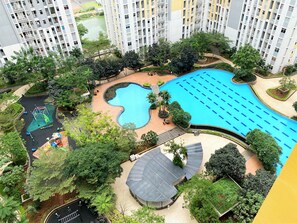 Residents enjoy a central pool surrounded by lush greenery and a winding path.