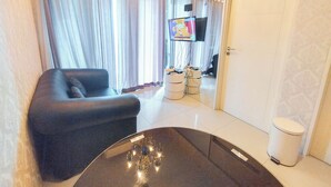A modern living room with a black sofa, a glass coffee table, and a TV mounted on the wall. - Best View 2BR Apartment Connected to Mall Tanglin Supermall Mansion Apartment (Surabaya)