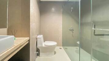 A modern bathroom with a glass-enclosed shower, a toilet, and a sink.