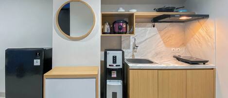 A compact kitchenette with a refrigerator, a coffee machine, a microwave, and a sink.