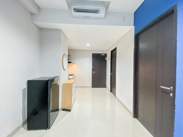 A hallway with a refrigerator, a wooden cabinet, and a door.