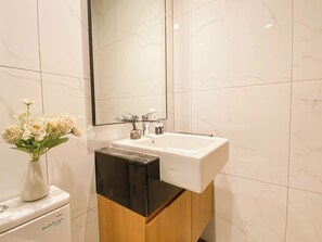 A bathroom with a white sink, a mirror, and a toilet. - Comfy Studio at Ciputra World 2 Apartment (Jakarta)