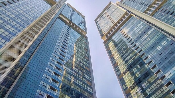 Een uitzicht op hoge, moderne wolkenkrabbers met reflecterende glazen gevels en een heldere lucht.