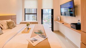 Een hotelkamer met een bed, een televisie, een bureau en een raam met uitzicht op de stad.