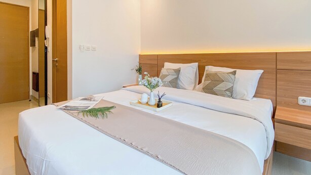 Ein modernes Hotelzimmer mit einem großen Bett, einem Holzkopfstück und einem Nachttisch mit einer Lampe.