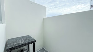 A small balcony with a black table and a metal stool. - Good Place 1BR at Menara Kebon Jeruk Apartment (Jakarta)