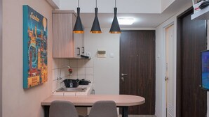 A compact kitchen with a wooden countertop, two chairs, a sink, and a painting of London landmarks. - Good Place and Homey 2BR at Apartment Serpong Greenview (South Tangerang)