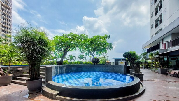Une piscine sur le toit, dont le fond présente un motif à carreaux, entourée de plantes en pot et avec un bâtiment moderne en arrière-plan.