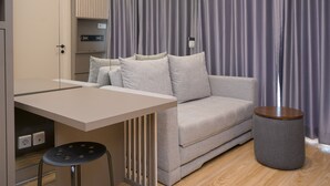 Un salon moderne avec un canapé, une petite table ronde et un tabouret.