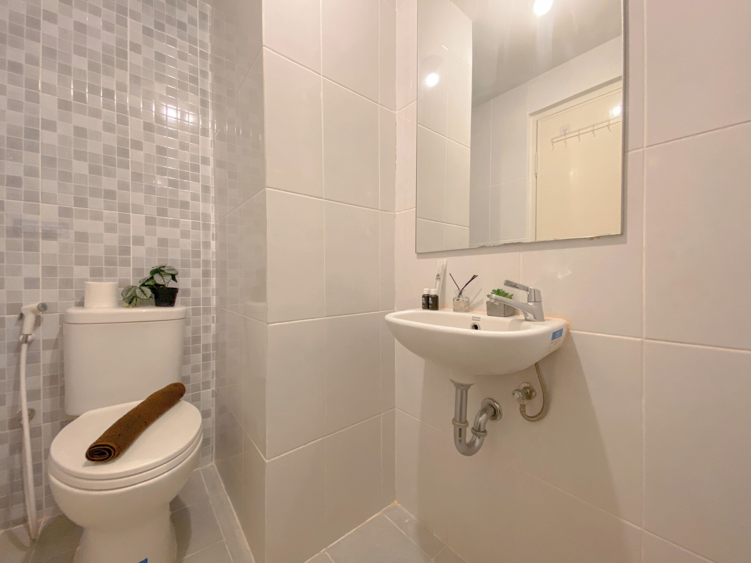 A bathroom with a toilet, sink, and mirror.