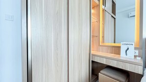 A hotel room with a wooden wardrobe, a mirror with a 'LONDON' sign, and a trash bin. - Comfy and Strategic 2BR Apartment at Signature Park Grande (Jakarta)
