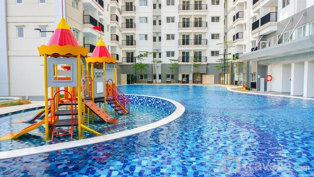 A swimming pool with a slide and a play structure, surrounded by a multi-story residential building. - Comfy and Strategic 2BR Apartment at Signature Park Grande (Jakarta)