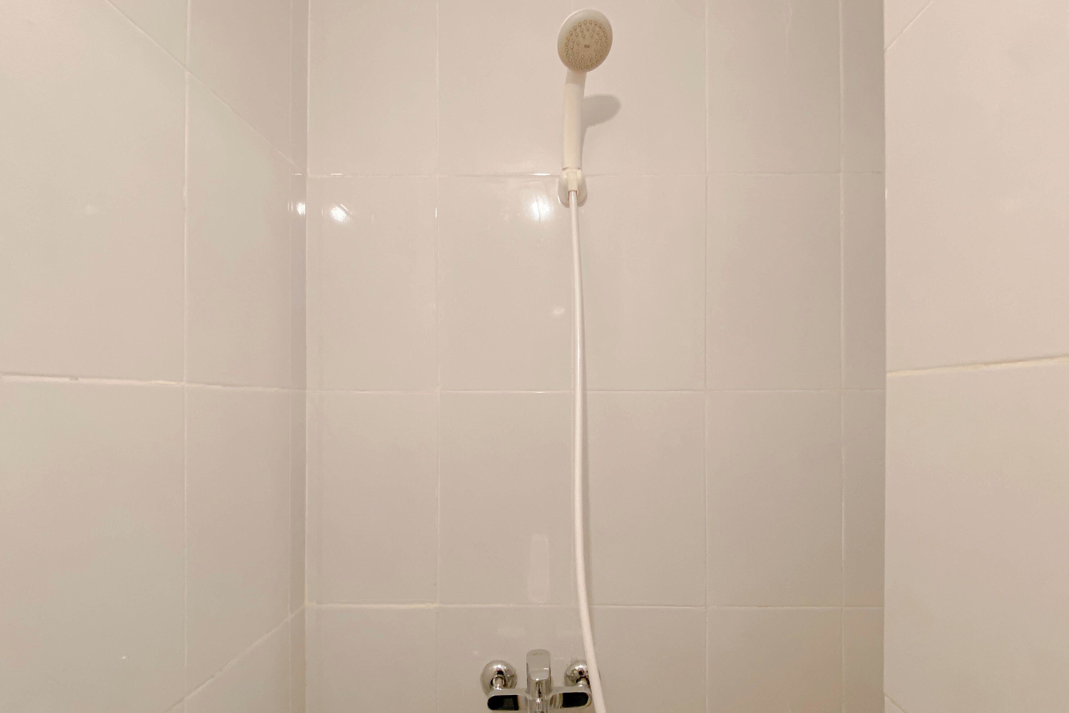 A shower with a handheld showerhead and a wall-mounted control valve.