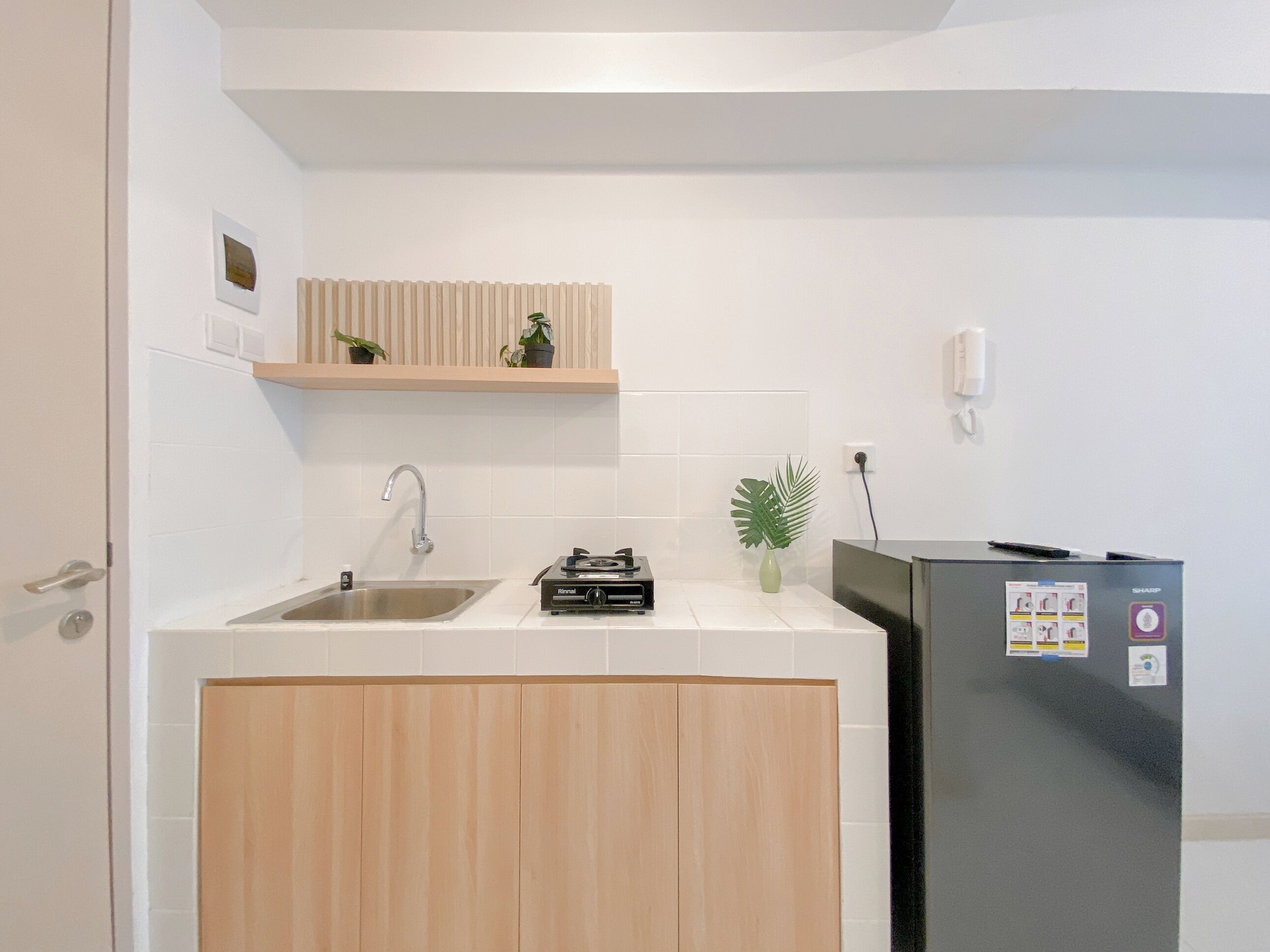 Eine kleine Küche mit Spüle, einer Arbeitsplatte, einem Einbauherd und einem Kühlschrank.