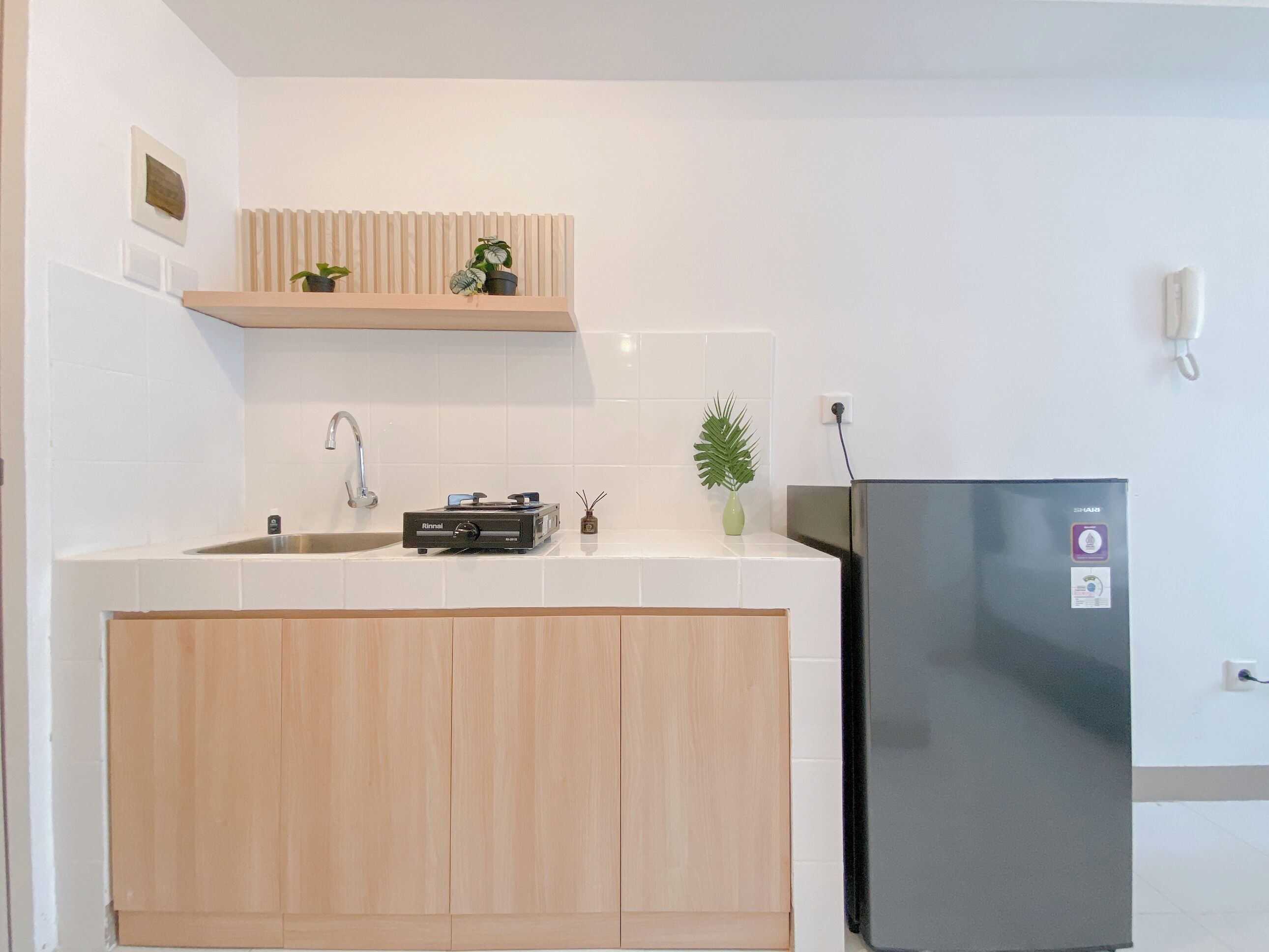 Une cuisine moderne dotée d’un évier encastré, d’un réfrigérateur noir et d’un meuble en bois situé sous le plan de travail.
