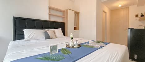 Habitación de hotel con una cama, una mesita de noche con un jarrón de flores y una pequeña mesa con una bandeja de objetos.