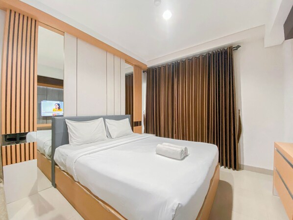 Een moderne hotelkamer met een groot bed, een flatscreen televisie aan de muur en een groot raam met gordijnen.