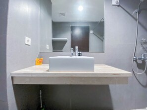 Een badkamer met een wit wastafel, een spiegel en een douche.