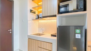 A compact kitchen with a built-in microwave, a stainless steel refrigerator, and a sink with a modern faucet.