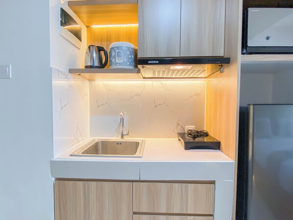 Una cocina moderna con un lavamanos de acero inoxidable, una cafetera y un microondas.