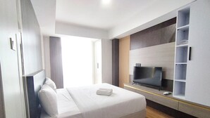 Et moderne hotelværelse med en stor seng, et fladskærms-tv og indbyggede hylder.