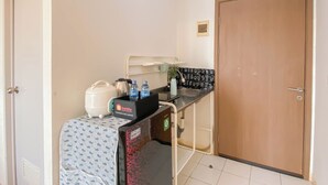 Cocina compacta con un lavamanos, una tetera, una cafetera y dos botellas de agua sobre la encimera.