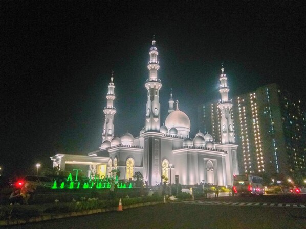 Una mezquita con cúpulas y alminares múltiples, iluminada durante la noche.