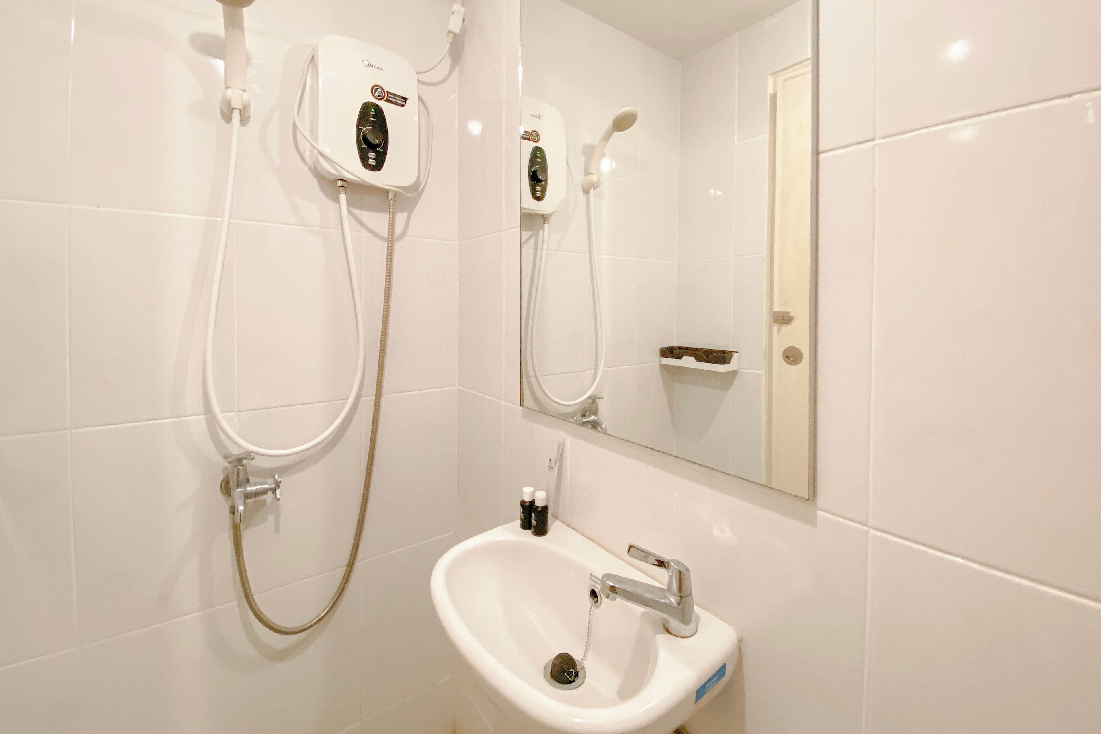 A bathroom with a white sink, a mirror, and a shower unit.