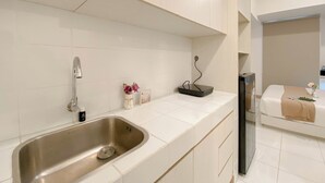 Ein modernes Badezimmer mit einem Edelstahlwaschbecken, weißen Fliesen und einem Bett mit einer beigefarbenen Decke.