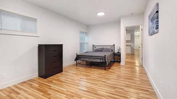 A bedroom with a bed, dresser, and a hallway leading to another room.