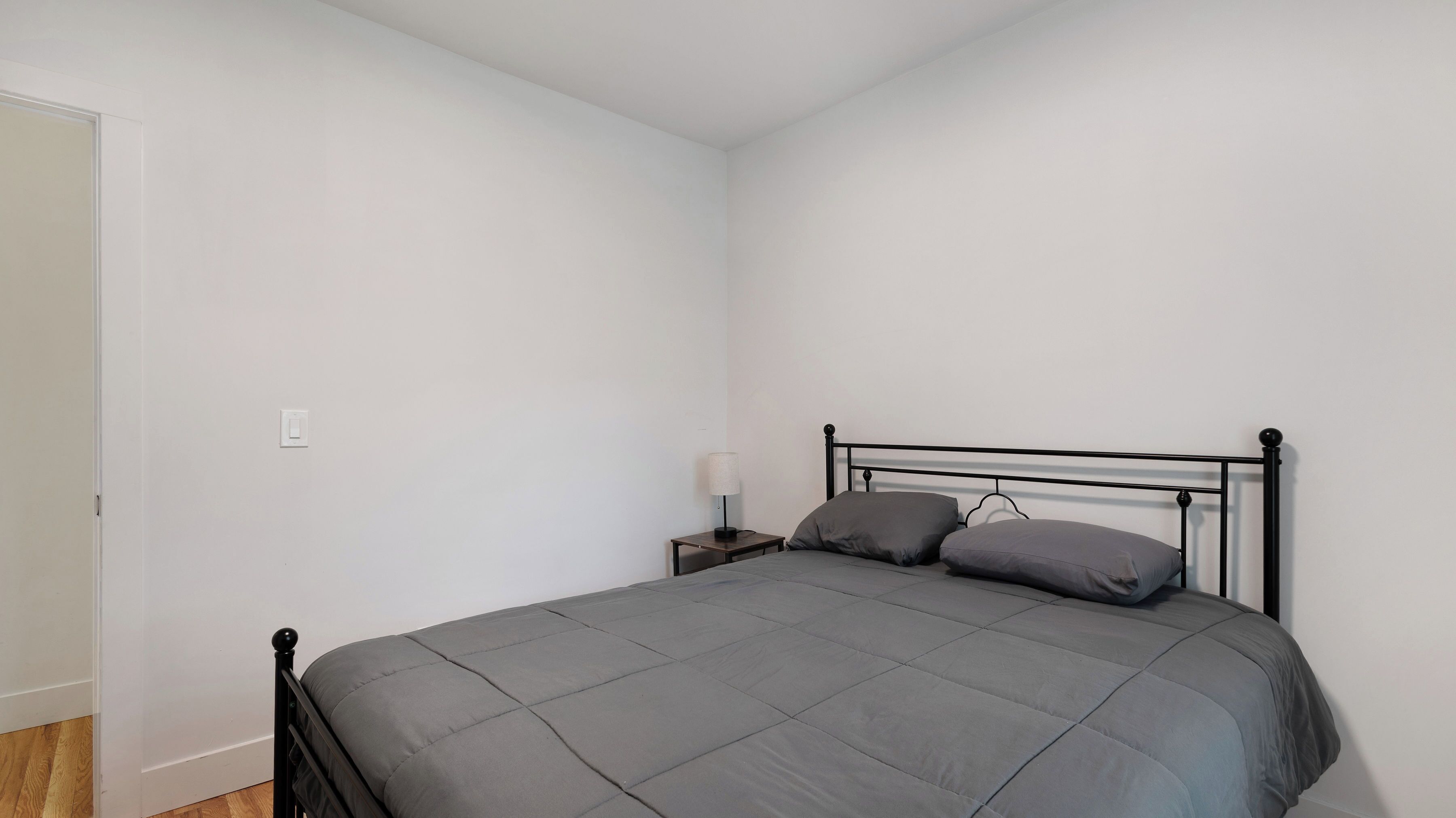 A bedroom with a bed, a nightstand, and a lamp.