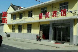 A two-story building with a yellow facade and a sign that reads '福润宾馆' (Fulong Inn). There is a motorcycle parked in front of the building.