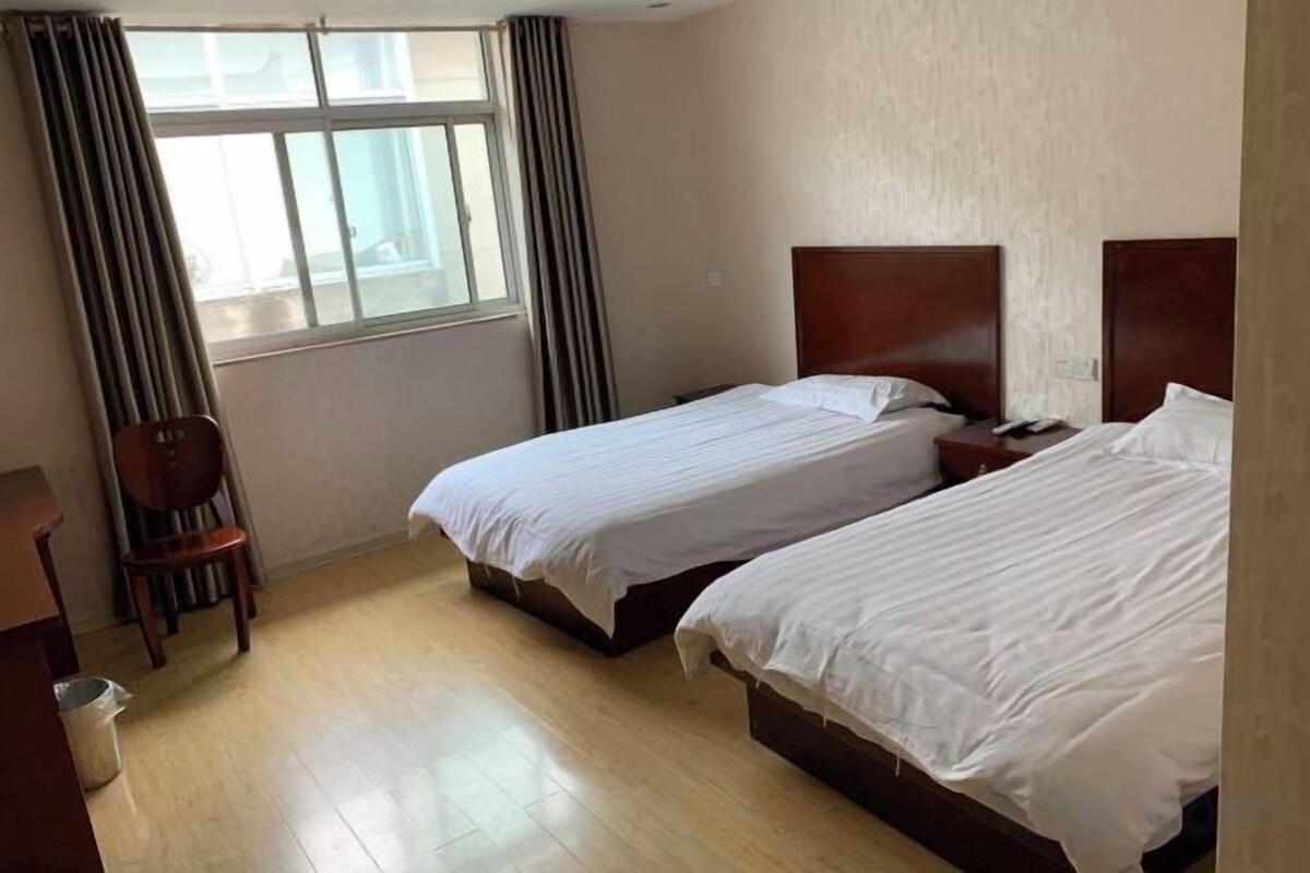 Une chambre d’hôtel avec deux lits, une chaise en bois et un bureau.