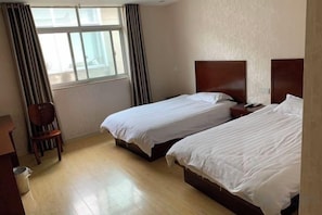 Une chambre d’hôtel avec deux lits, une chaise en bois et un bureau.