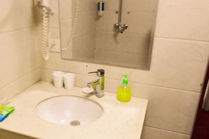 Une salle de bain équipée d’un lavabo, d’un miroir, d’une douche et d’un téléphone.