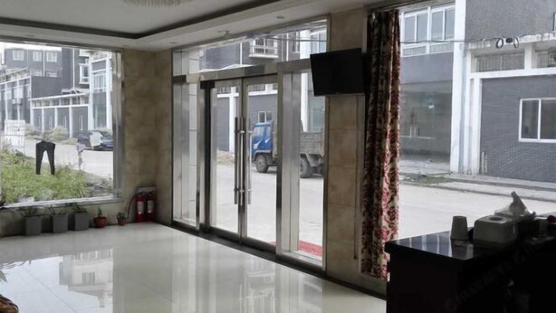 A hotel lobby with a large glass door, a reception desk, and a fire extinguisher near the entrance. - YangZhou FuRun Hotel (Yangzhou)