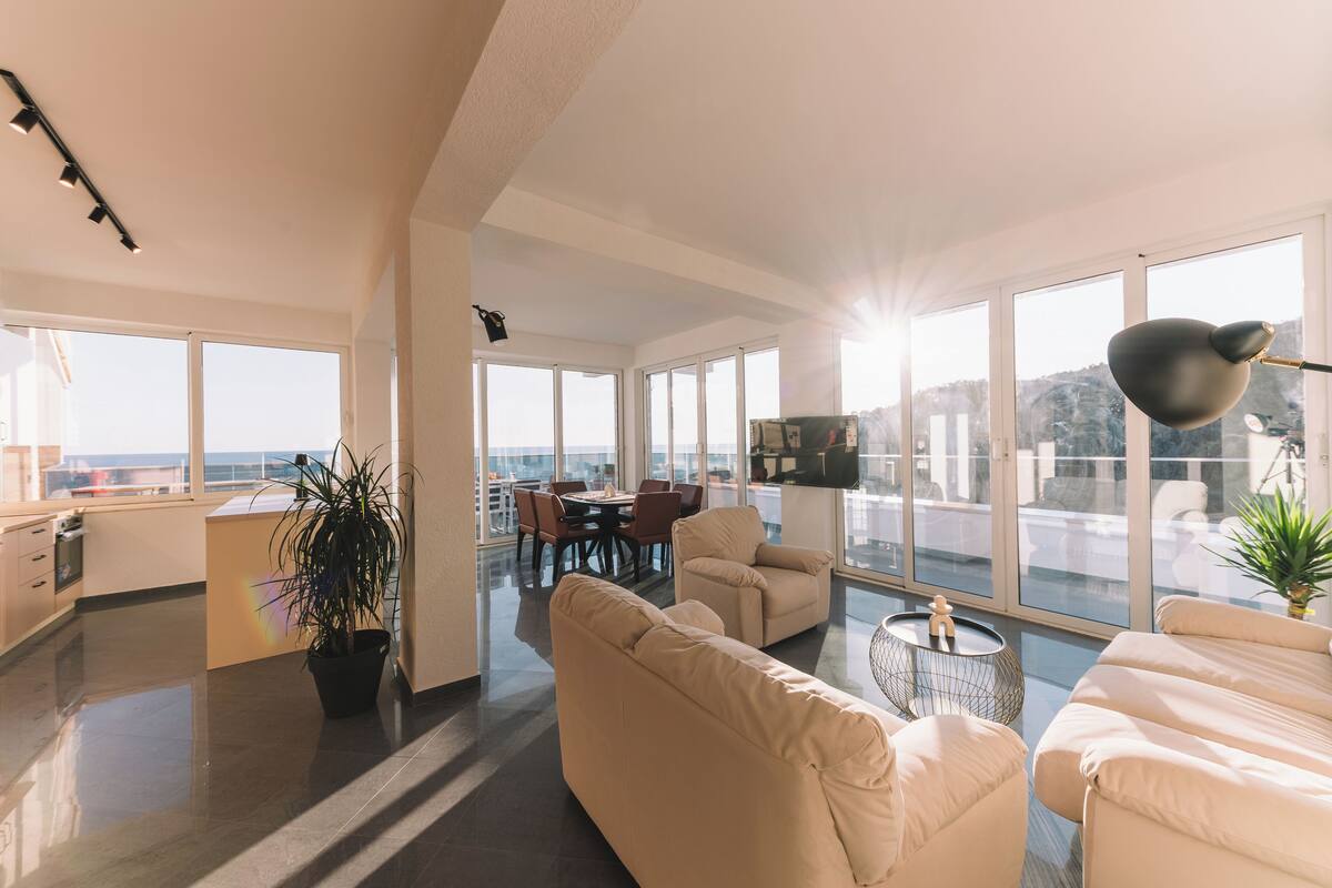 A spacious living area with a large window, a dining table, and a sofa.