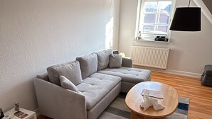A modern living room with a grey sectional sofa, a wooden coffee table, and a striped rug.