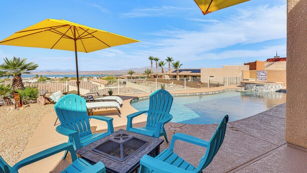 Un espace aménagé au bord de la piscine, avec des chaises bleues, une table et un parasol jaune.